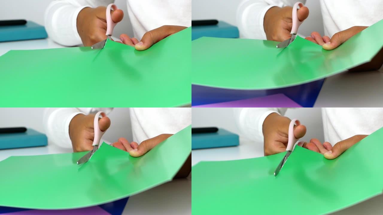 一个小女孩用自己的手雕刻假货，用剪刀从彩纸上剪下来。特写4k视频。