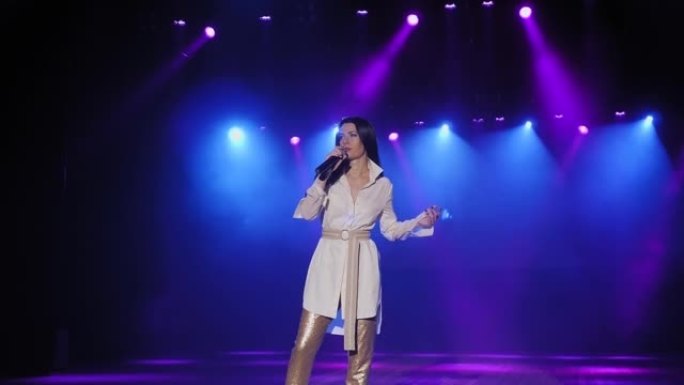 一个穿着白色西装的歌手在舞台上唱歌，手里拿着麦克风。