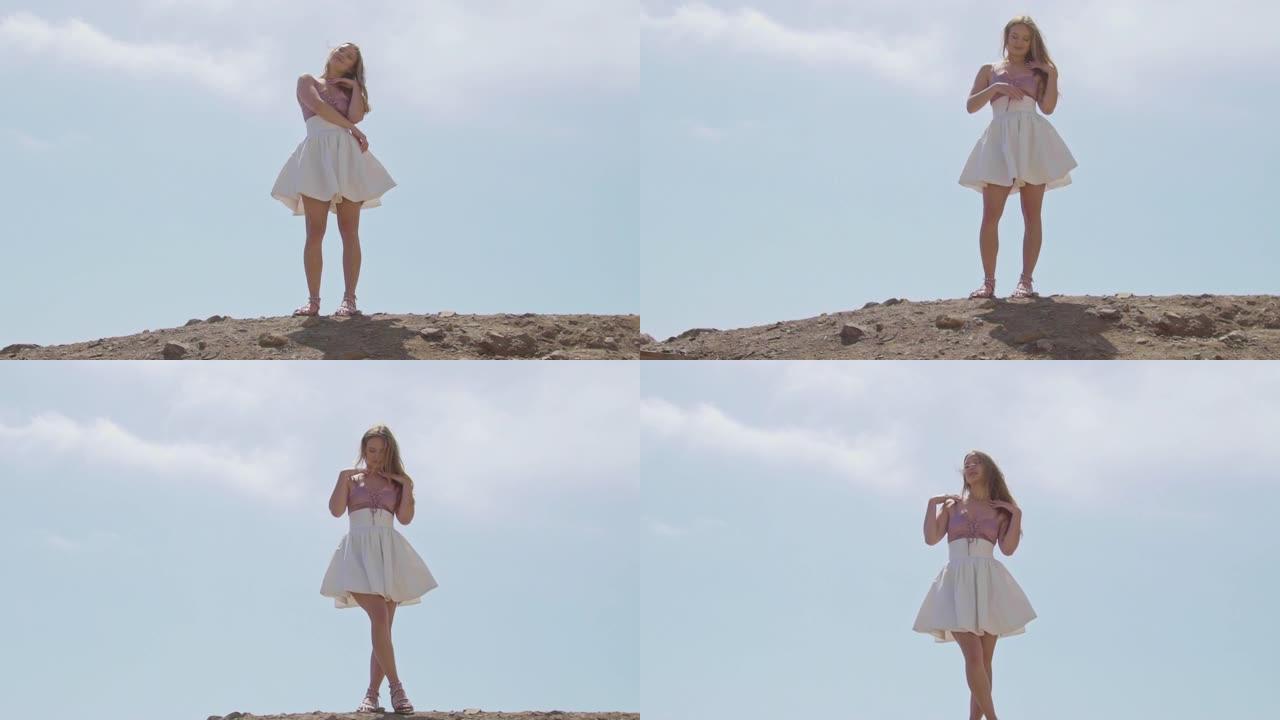 穿着粉色和白色裙子上衣的漂亮女孩在悬崖上户外摆姿势