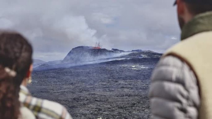 两名勇敢的游客观看冰岛爆发的火山的美丽航拍