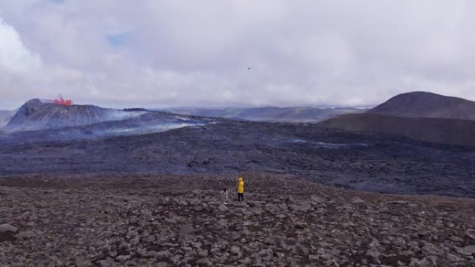 两名探险家在野外的空中射击，并看到一座喷发的火山