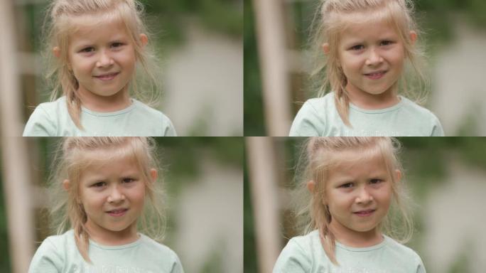 美丽的金发小女孩在夏日微风中站在外面，微笑着，摆姿势时看起来很无辜