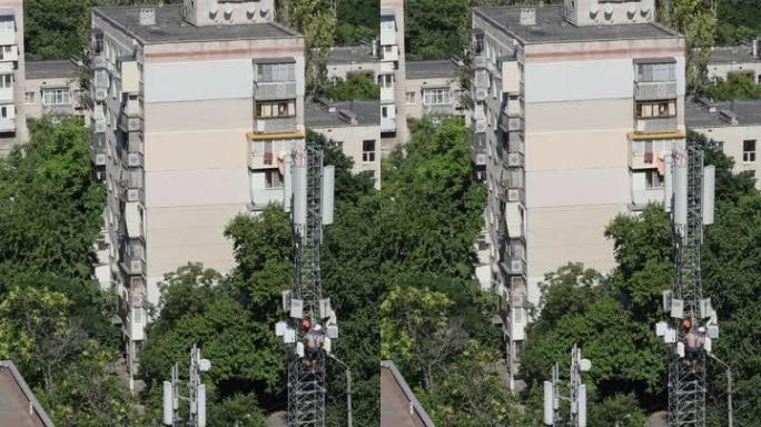 在带有通讯塔的建筑屋顶上无法识别的建筑工人