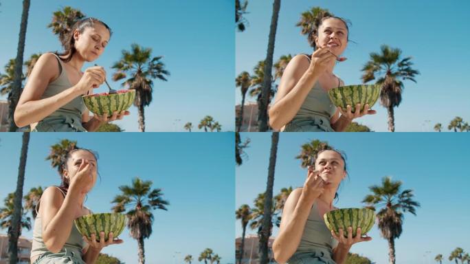 在晴朗的日子里，女孩在棕榈树公园里用勺子吃西瓜