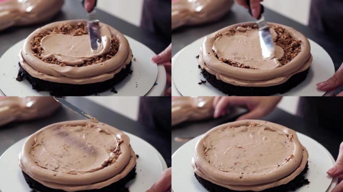 4k糕点厨师将奶油榛子馅料涂在巧克力海绵蛋糕上，特写镜头。慢动作。蛋糕制作过程