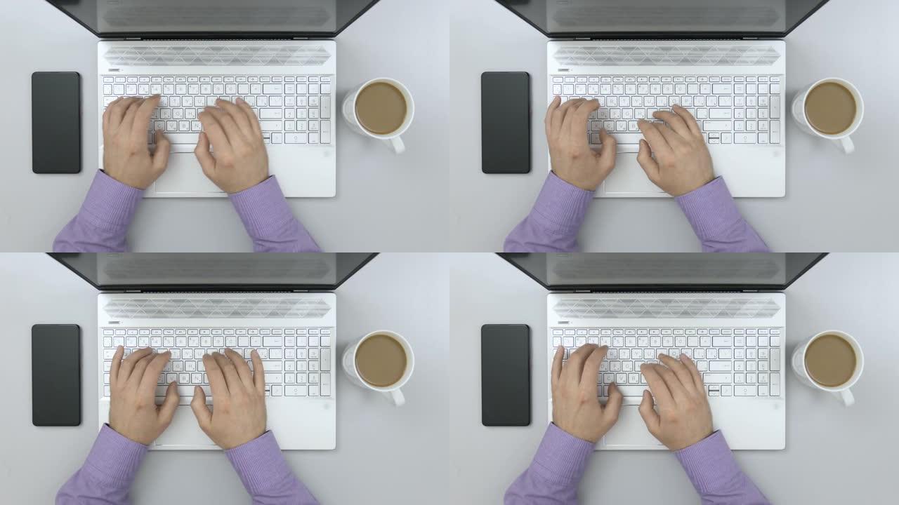 商人在木制灰色桌子上的笔记本电脑上打字。俯视图学生学习。创意设计师工作台的俯视图。在台式计算机上工作