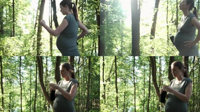 活跃的孕妇在夏季公园散步，停下来喘口气，喝水。准妈妈锻炼健康的生活方式户外慢跑锻炼。怀孕运动和健身训