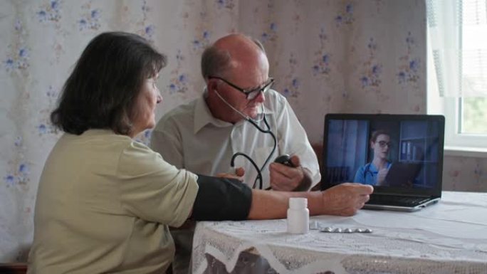 保健和预防，养老金领取者用眼压计测量妻子的血压，老年夫妇与专业女医生远程咨询