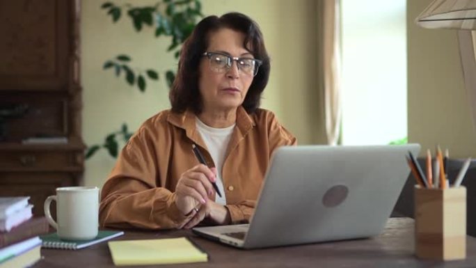 自信认真的成熟女人在家里的笔记本电脑视频通话中交谈。讨论商业项目