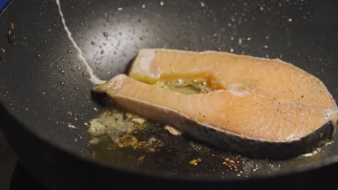 有人把黄油炒三文鱼放在黑锅上。低卡路里的健康菜单。