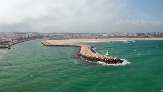 葡萄牙阿尔加维拉各斯海岸线防波堤结构的鸟瞰图，无人机在多风的海面上盘旋，白天