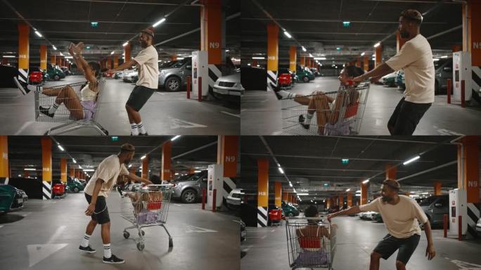 年轻的非洲裔美国人骑着他快乐的黑人女友在购物中心地下停车场的购物车里，慢动作