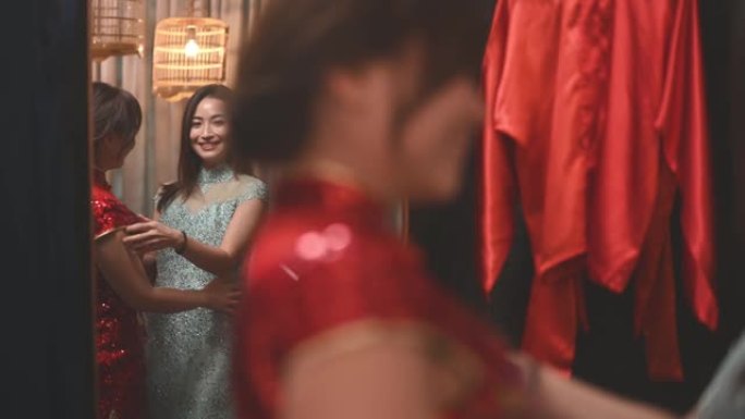 亚洲中国妇女在传统精品店试穿传统旗袍照镜子