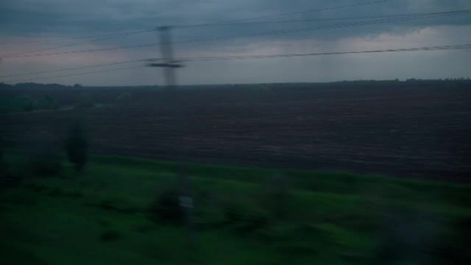 从高速火车的窗户上可以看到美丽的自然野外和森林的风景，傍晚多云的黄昏天空日落在夏天的背景下。交通、旅