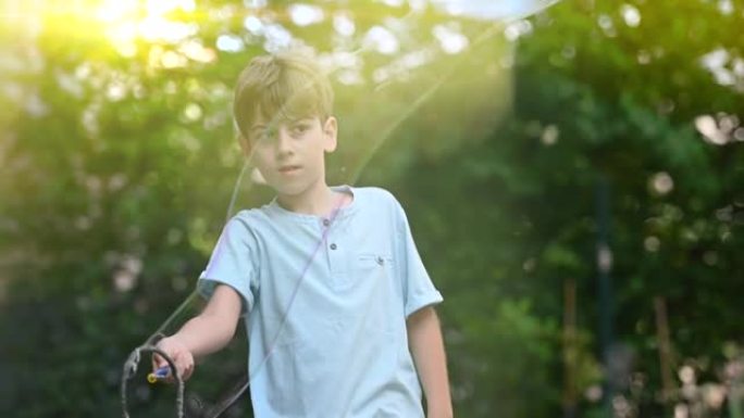 一个小男孩拿着一根巨大的泡泡棒在后花园玩耍。