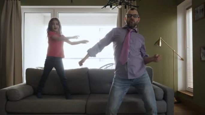 快乐的爸爸女儿在客厅里欢快地跳舞。快乐的父亲和女儿在家里的客厅跳舞，有趣的庆祝有趣的病毒舞蹈自由周末