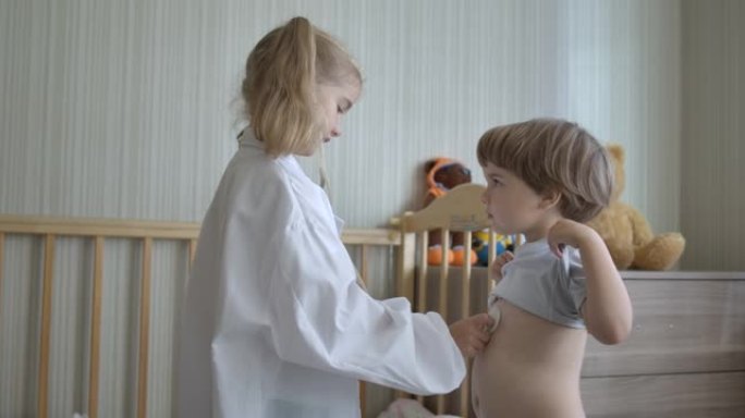 可爱的小孩穿着医疗制服在家玩耍。创意儿童女孩和男孩医疗制服听诊器。儿童玩游戏作为医生和病人。