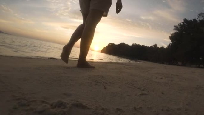 晚上夏天日落时，女人赤脚独自在沙滩上行走的特写镜头