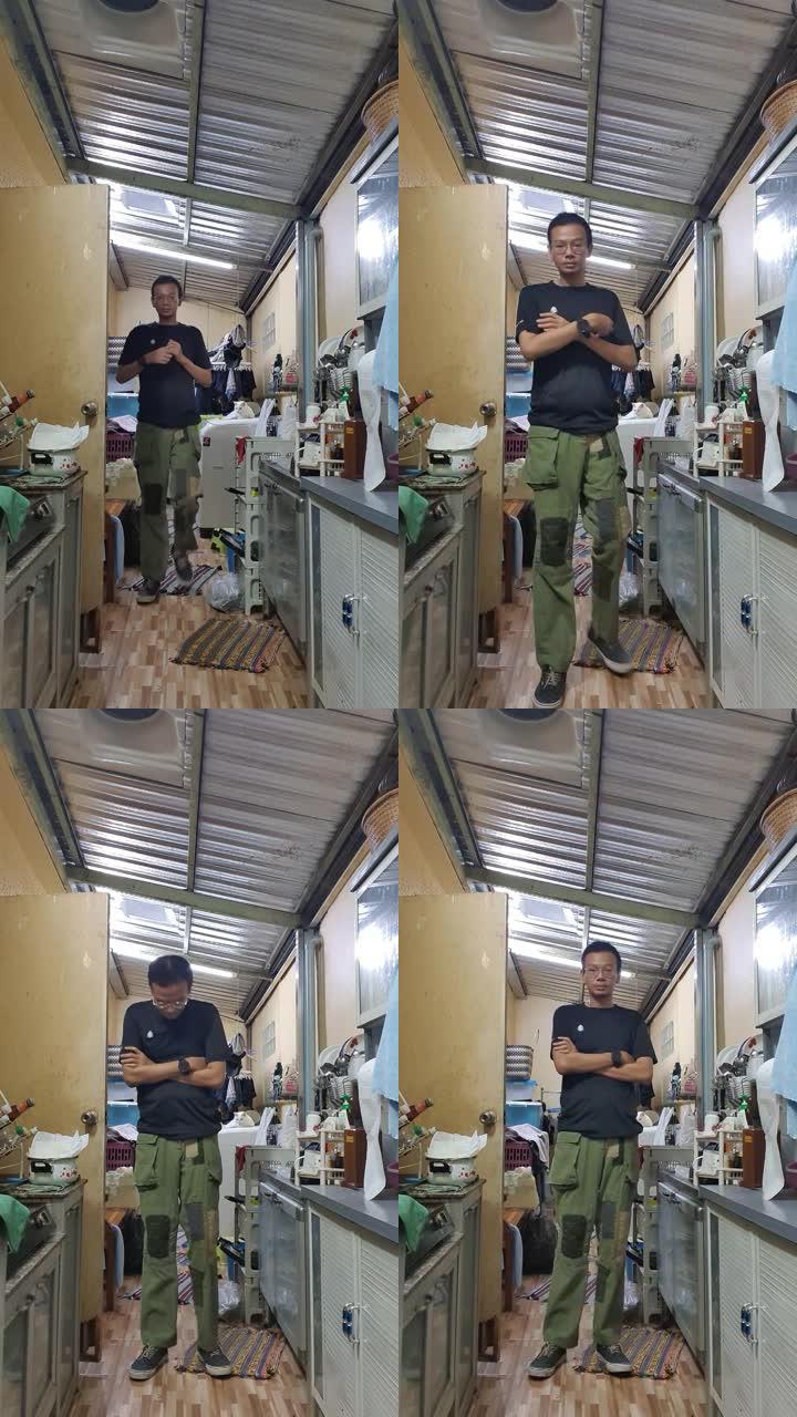 一个穿着黑色t恤和绿色货物的男人在厨房里行走。