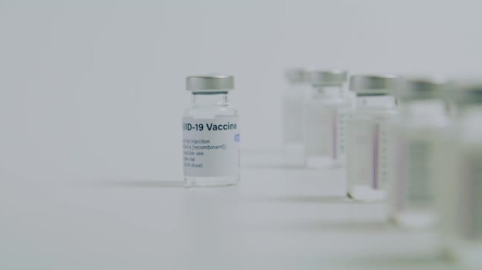 科学家或医生的手把新型冠状病毒肺炎疫苗瓶从生产线上拉出来