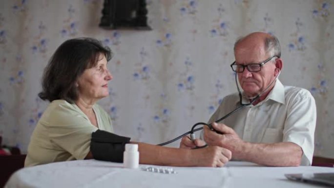 退休男子使用眼压计测量坐在家里的妻子的血压，高血压和低血压