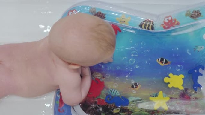 可爱的男婴在浴室玩儿童充气水气垫，婴儿活动玩水垫水下世界婴儿气垫垫。