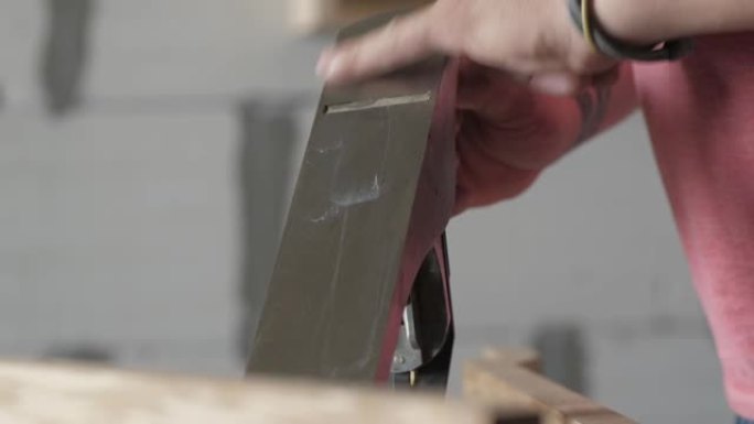 男性工人用油润滑手平面的刀片。木匠用润滑脂润滑飞机。木工艺术。