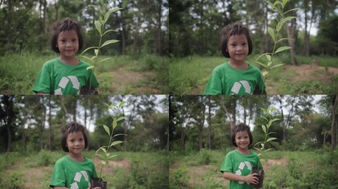 可爱的女孩站着拿着一棵植物，她准备在森林里种一棵树。