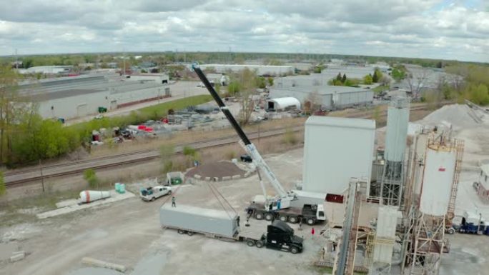 起重机在工厂卸下承运人的卡车。在宽的空中无人机视图上方。
