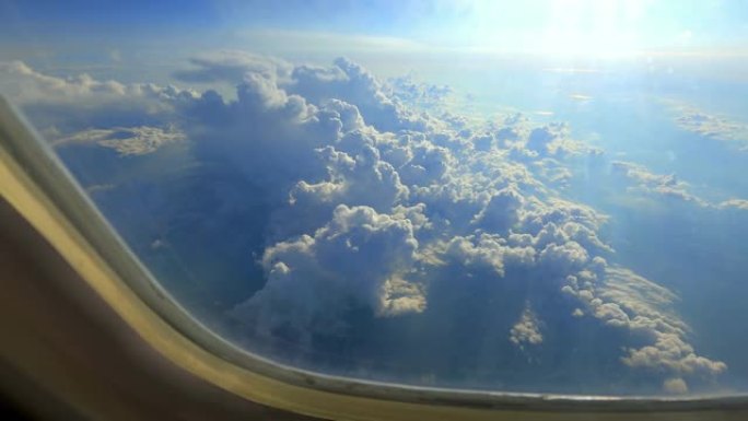 太阳从云层穿过飞机窗户越过山脉