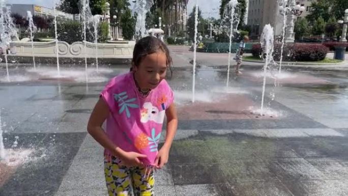 4k微笑的小女孩在喷泉附近散步后湿了。