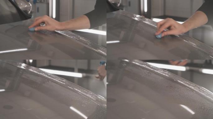 在将保护层或PPF涂层安装到汽车上之前，工人用蓝色粘土清洁车身以进行清洁。汽车细节概念