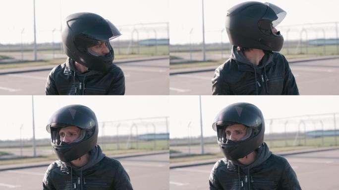 年轻迷人的摩托车手，戴着黑色头盔和黑色皮夹克。男子摩托车手