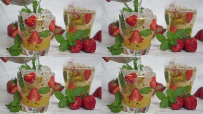 将苏打水倒入装有薄荷和冰块的百香果鸡尾酒的玻璃杯中，自制的新鲜水果配以苏打水，西番莲和草莓甜水果饮料