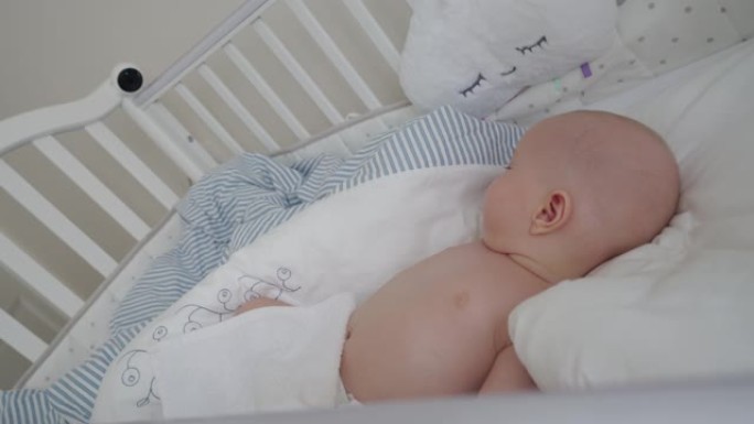男婴睡在婴儿床里，婴儿床安装了IP无线安全摄像头作为婴儿监视器，内部是现代公寓卧室。