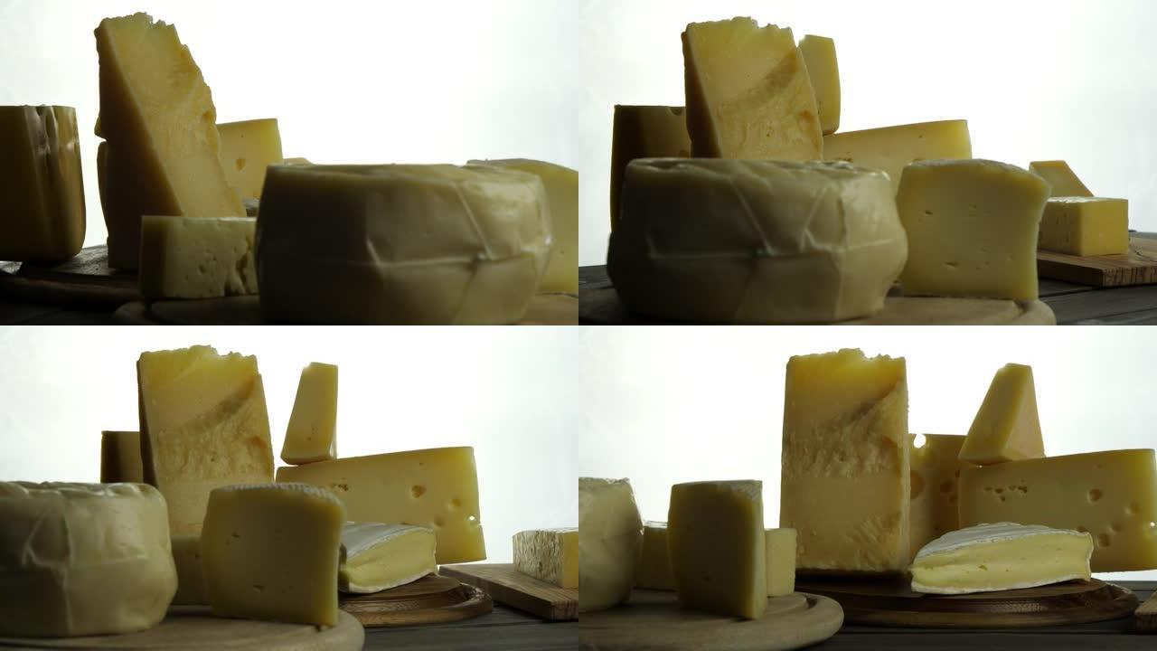 木盘上不同类型奶酪的静果，意大利戈贡佐拉，帕尔马干酪，法国布里干酪，木砧板上奶酪慢速旋转视频