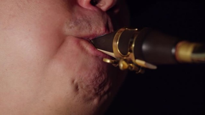 男性萨克斯管演奏者在特写镜头中吹入萨克斯管的嘴。音乐家演奏萨克斯管，吹入烟嘴