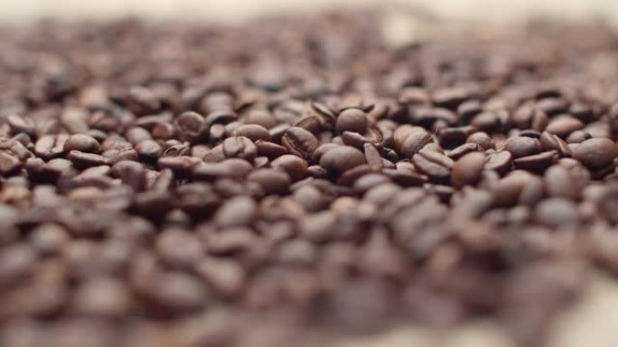 棕色烤咖啡豆落在一束棕色豆子上。以飞香咖啡种子的形式来形象早餐，能量和活力的概念，特写