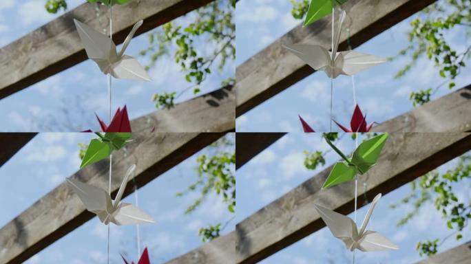 绳子上的白纸鹤在风中摇摆。公园里的日本折纸人物