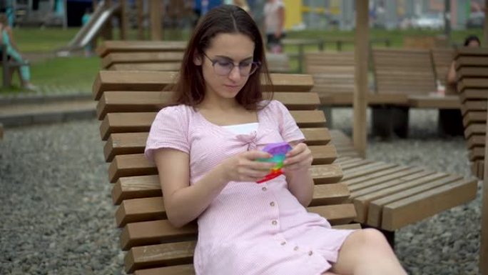 一个愤怒的女人躺在躺椅上，手里拿着流行的玩具。那女孩玩玩具以使自己平静下来。
