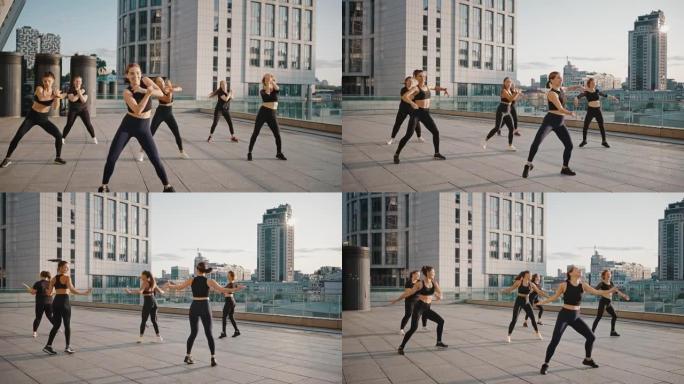 在城市背景上跳舞尊巴舞的年轻女性。一群女孩在练习户外体育舞蹈，志同道合的女人在街上训练