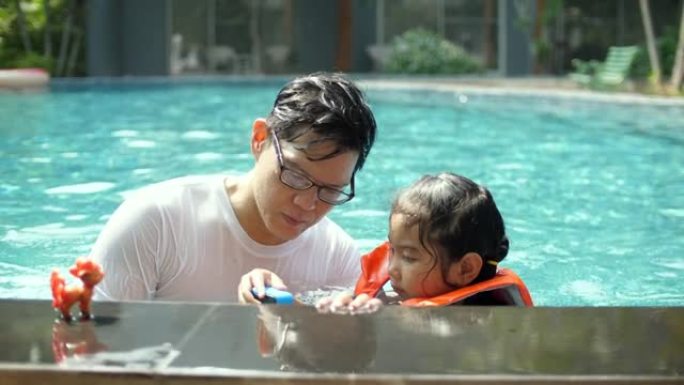 父亲和他的女儿在游泳池里玩得开心，在阳光明媚的日子里使用运动相机