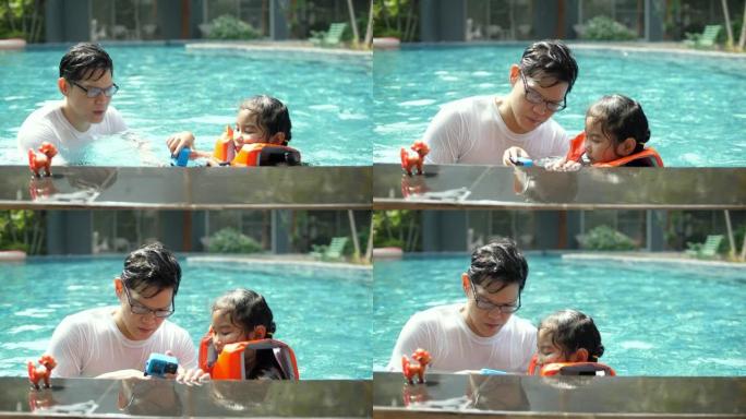 父亲和他的女儿在游泳池里玩得开心，在阳光明媚的日子里使用运动相机