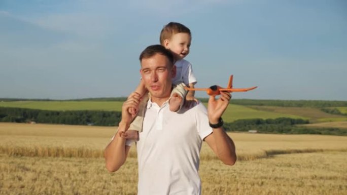 男子将蹒跚学步的儿子扛在肩上，手握玩具飞机
