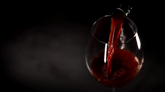 红酒从黑色背景的瓶子里倒入玻璃杯中。复制空间