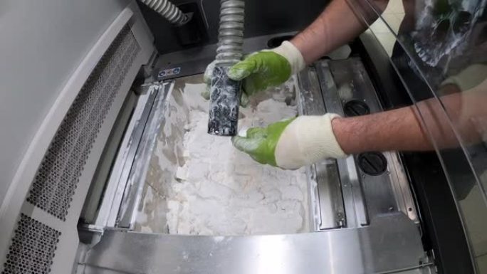 Man用白色塑料粉末清洁工业3D打印机上打印的细节。