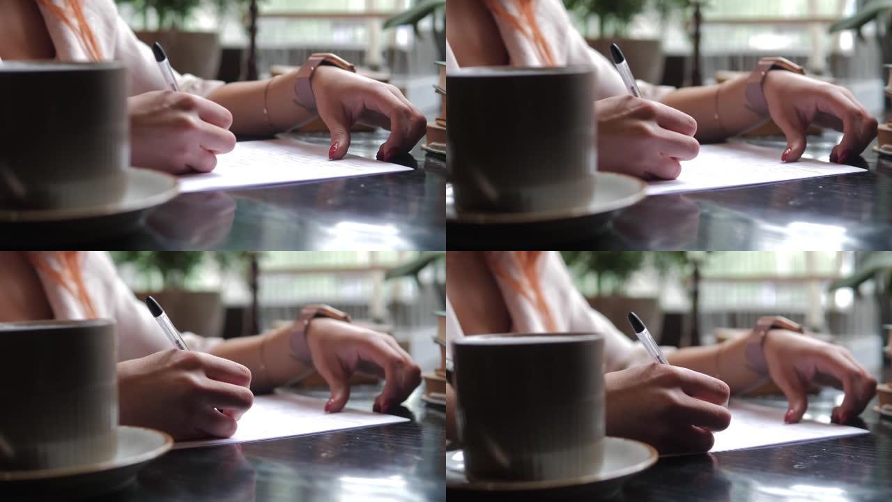 女孩在白纸上手写一封信。一种老式的写信方式。用笔在纸上写字的特写镜头。写书的提纲。一杯咖啡。