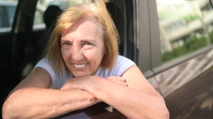 快乐的高级女人开车坐在新的棕色汽车，微笑着看着相机享受旅程。驾驶课程和人寿保险概念。退休人员活动理念