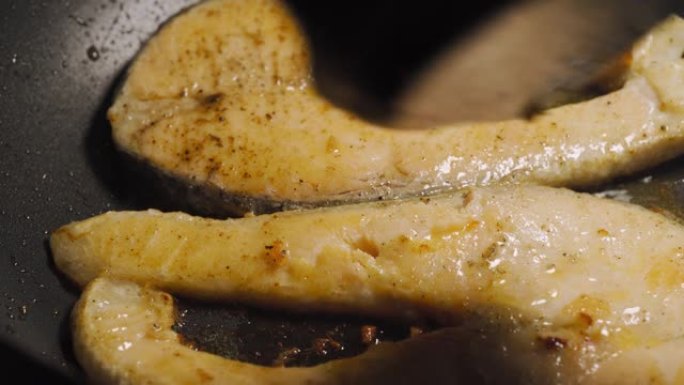 黄油炸三文鱼在黑锅上翻动。低卡路里的健康菜单。