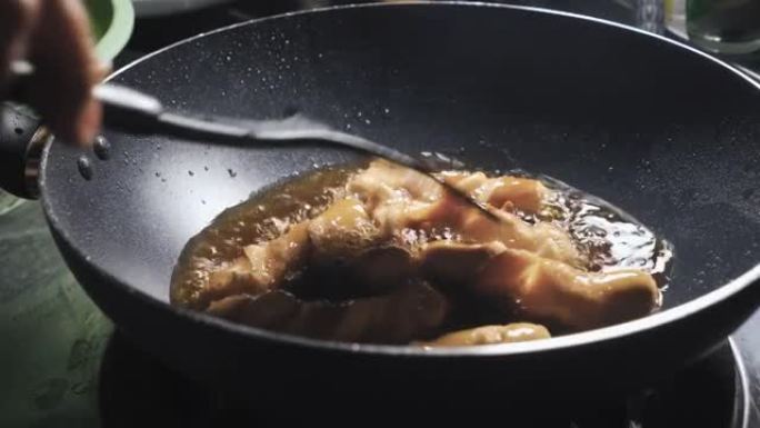 香肠在装满沸腾油的锅中煎炸。脆皮和垃圾食品菜单。泰国美味的菜单。特写镜头。